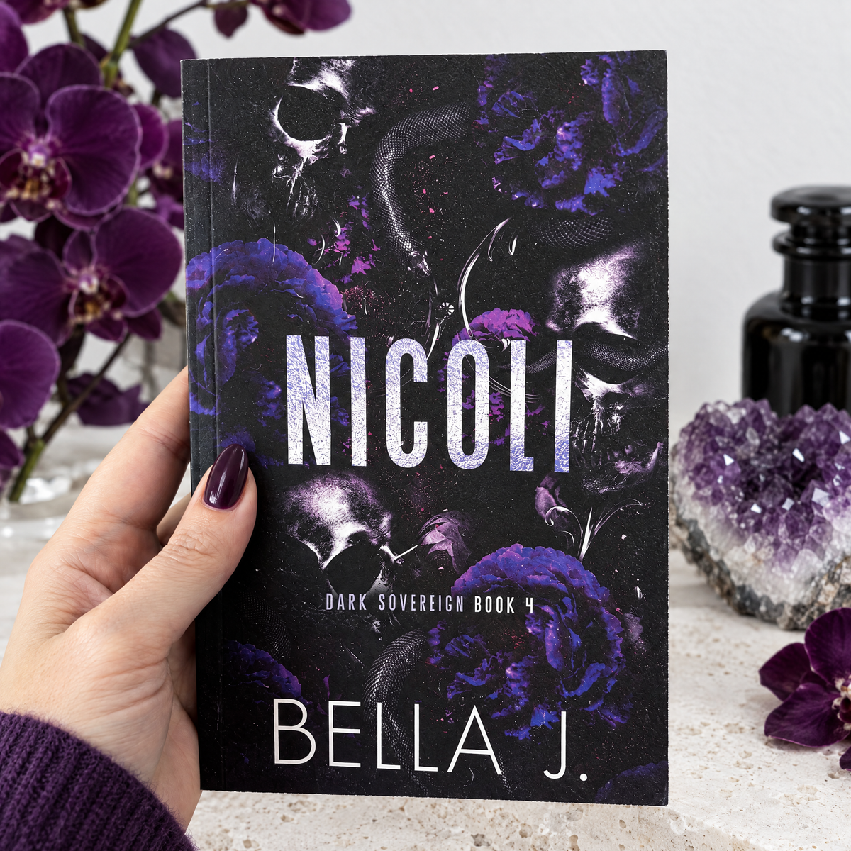 Hand holding a signed paperback of Nicoli by Bella J., discreet cover, Dark Sovereign book 4