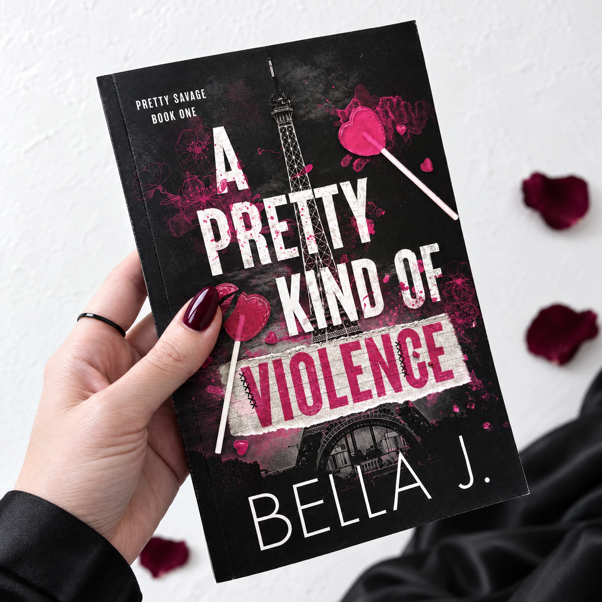 Hand holding a signed paperback of A Pretty Kind of Violence by Bella J., Pretty Savage book 1