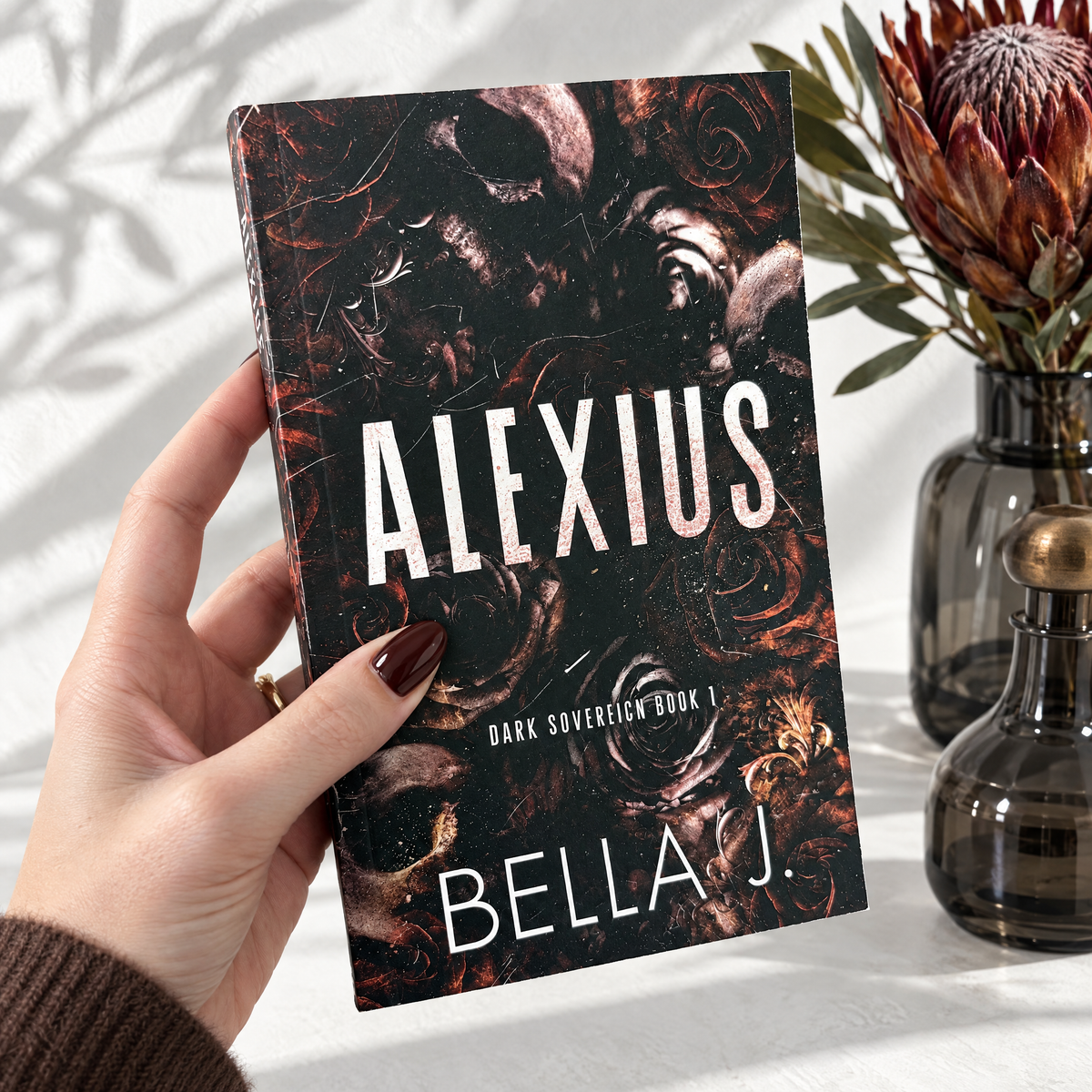 Hand holding a signed paperback of Alexius by Bella J., discreet cover, Dark Sovereign book 1