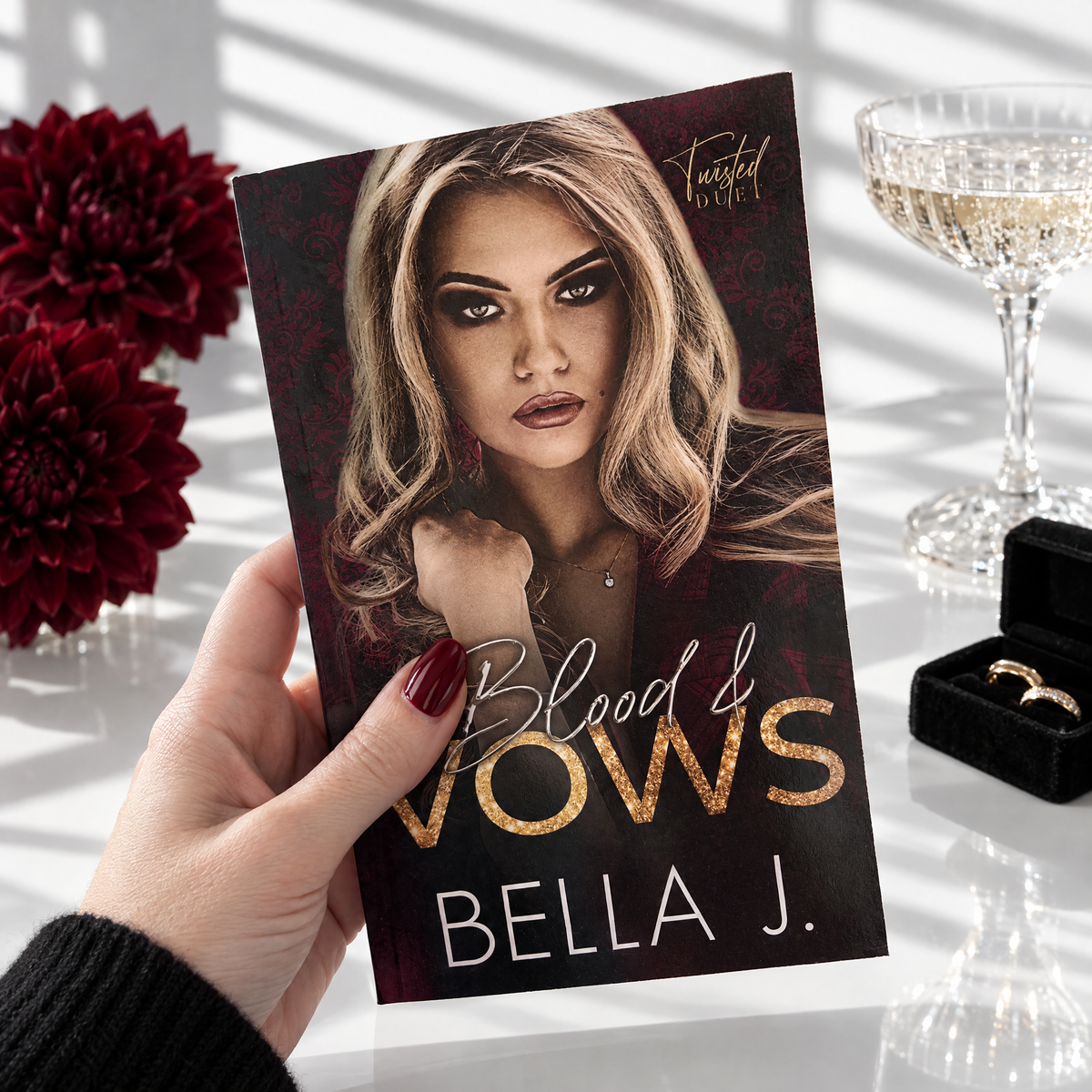 Hand holding a signed paperback of Blood and Vows by Bella J., model cover, Twisted Duet book 2